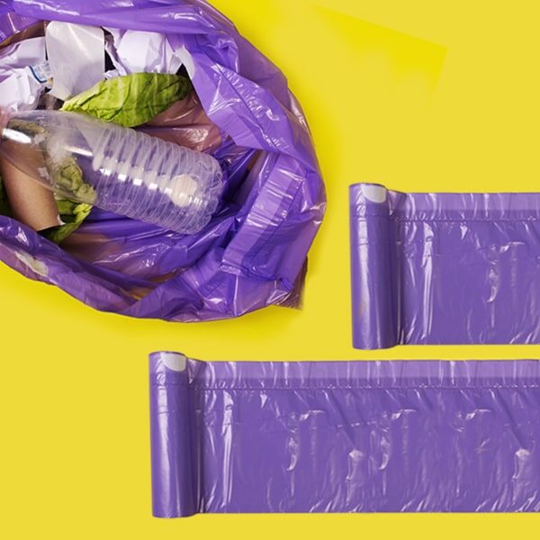 rotoli di sacchetti rifiuti viola con sacco rifiuti e spazzatura visti dall'alto su fondo giallo