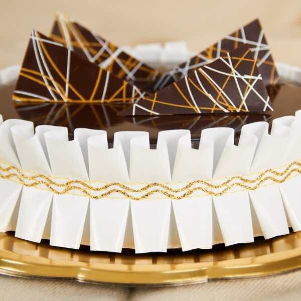 torta con glassa al cioccolato con giro torta in carta bianca e oro