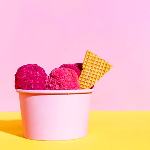 coppetta di gelato in cartoncino rosa con gelato alla fragola e cialda biscotto
